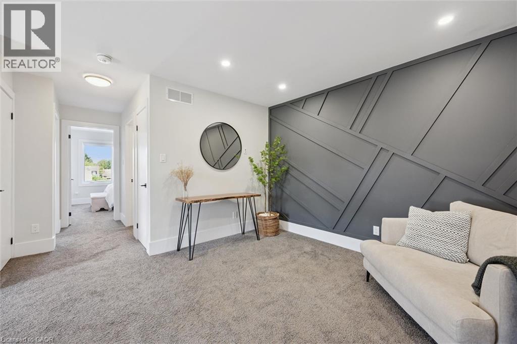 Accent wall featuring geometric paneling, recessed lighting, and light gray carpeting - 63 Plymouth Road, Kitchener, ON