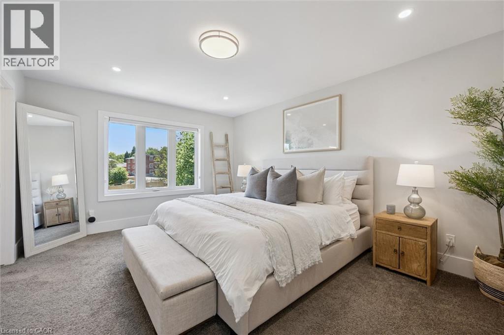 Bright bedroom featuring a large multi-pane window, recessed lighting, a ceiling-mounted light fixture, and plush carpeting - 63 Plymouth Road, Kitchener, ON