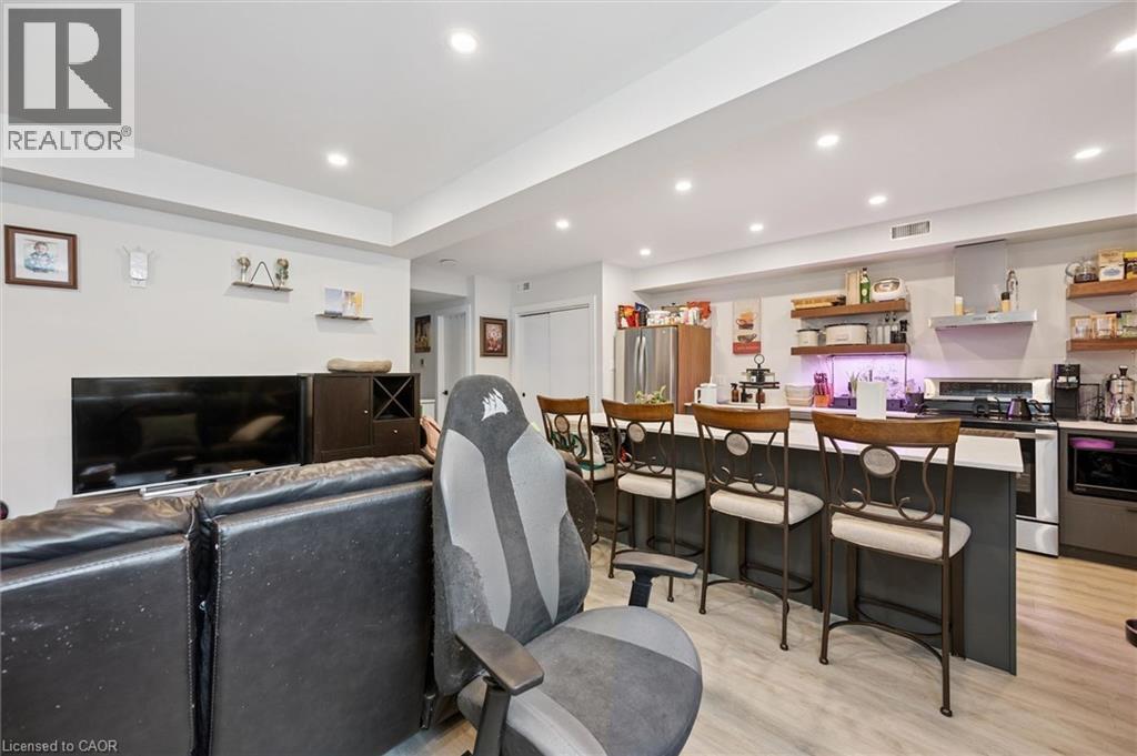 Open-concept living space featuring recessed lighting, light wood-finish flooring, and a kitchen island with seating - 63 Plymouth Road, Kitchener, ON