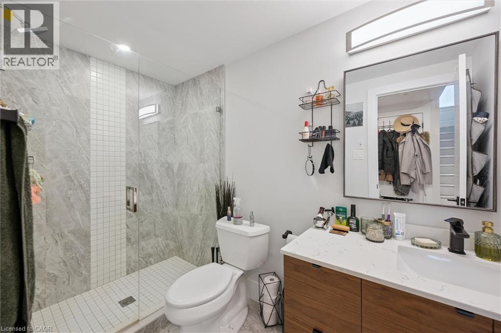 Modern bathroom featuring a glass-enclosed shower with large format tile and a contrasting mosaic accent strip - 63 Plymouth Road, Kitchener, ON