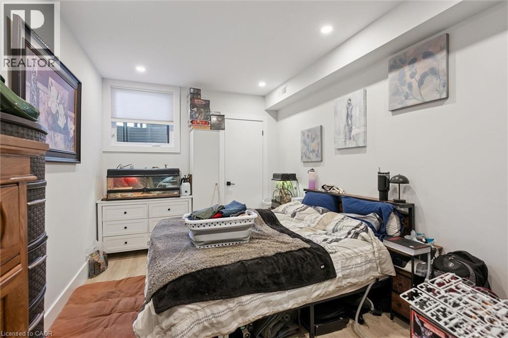 Recessed lighting illuminates this room featuring light wood-finish flooring, white baseboards, and a white interior door with black hardware - 63 Plymouth Road, Kitchener, ON