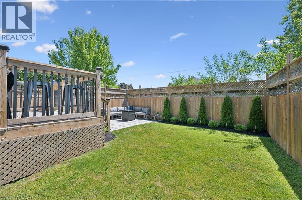 Expansive backyard featuring a lush lawn, privacy fencing, and a multi-level outdoor living space - 63 Plymouth Road, Kitchener, ON