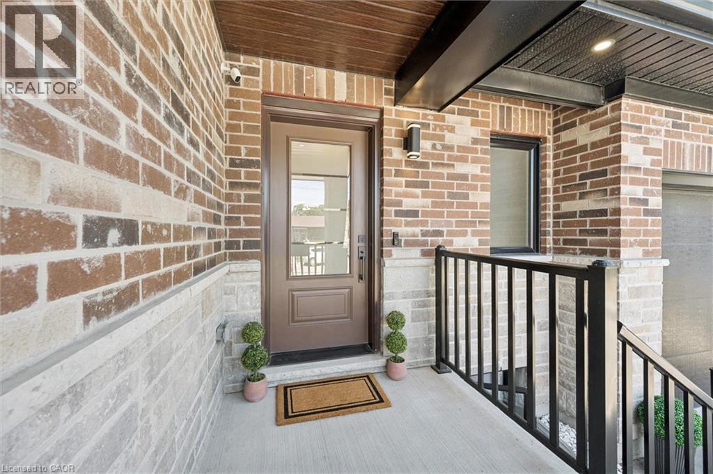 Entryway featuring a solid wood front door with a glass insert, complemented by brick and stone veneer siding - 63 Plymouth Road, Kitchener, ON