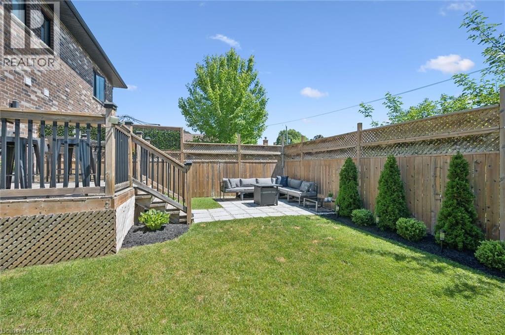 Expansive backyard featuring a manicured lawn and a paver patio - 63 Plymouth Road, Kitchener, ON