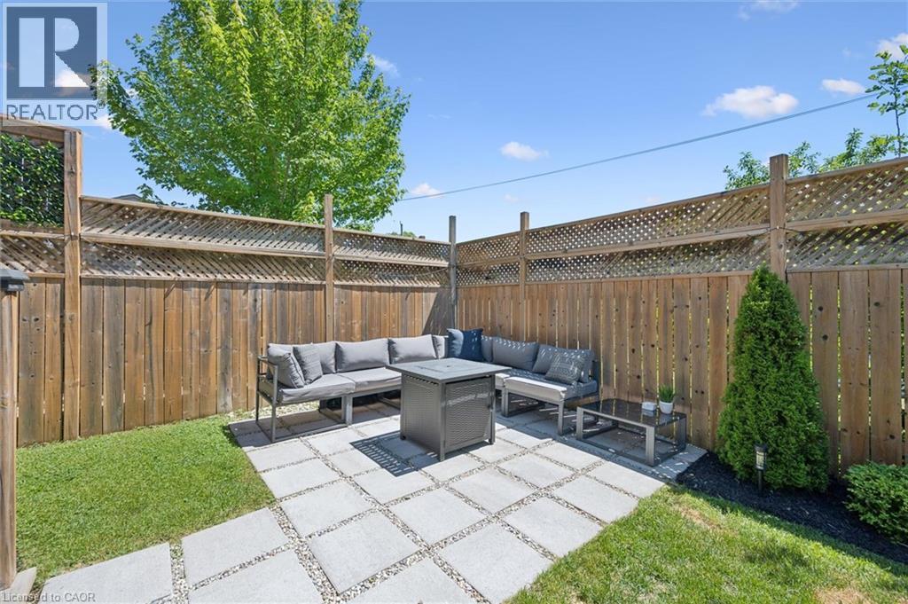 Private backyard patio featuring large format pavers, gravel accents, and perimeter fencing with lattice details - 63 Plymouth Road, Kitchener, ON
