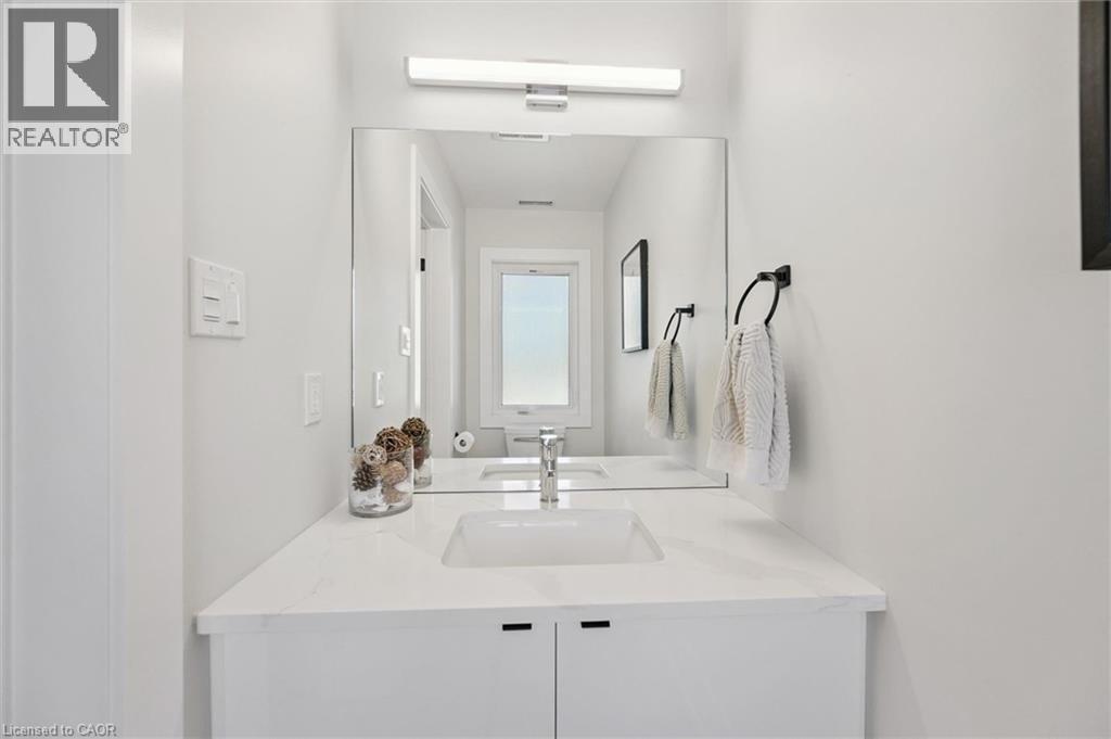 Modern vanity featuring a white rectangular undermount sink, a white stone-finish countertop, and white cabinetry with integrated pulls - 63 Plymouth Road, Kitchener, ON
