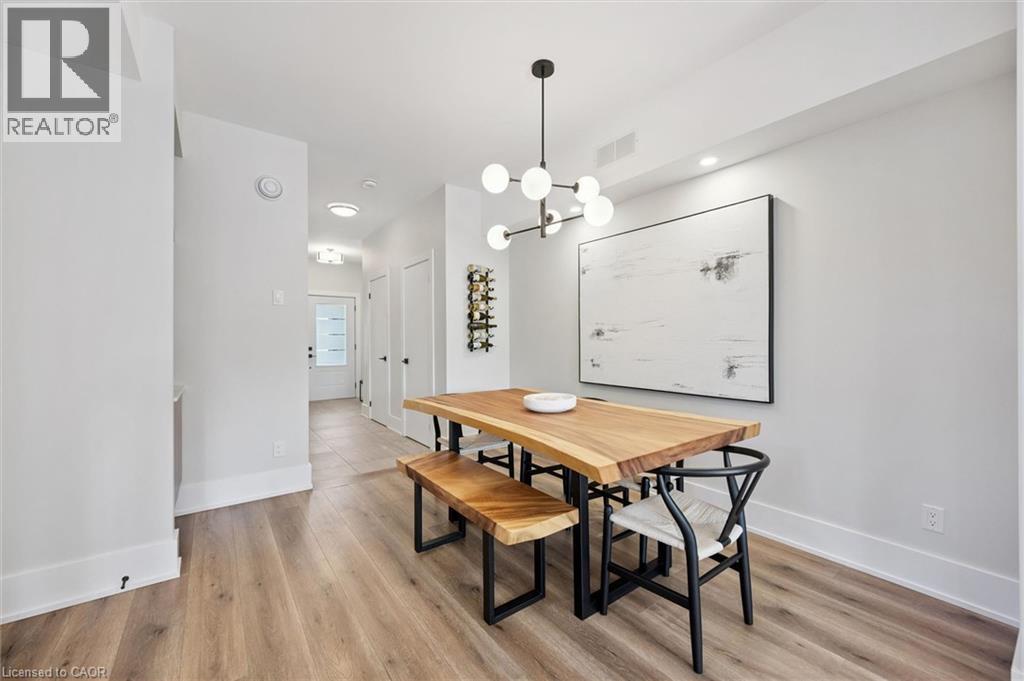 Dining area featuring wood-finish flooring, a contemporary chandelier, recessed lighting, and crisp white walls with matching baseboards - 63 Plymouth Road, Kitchener, ON