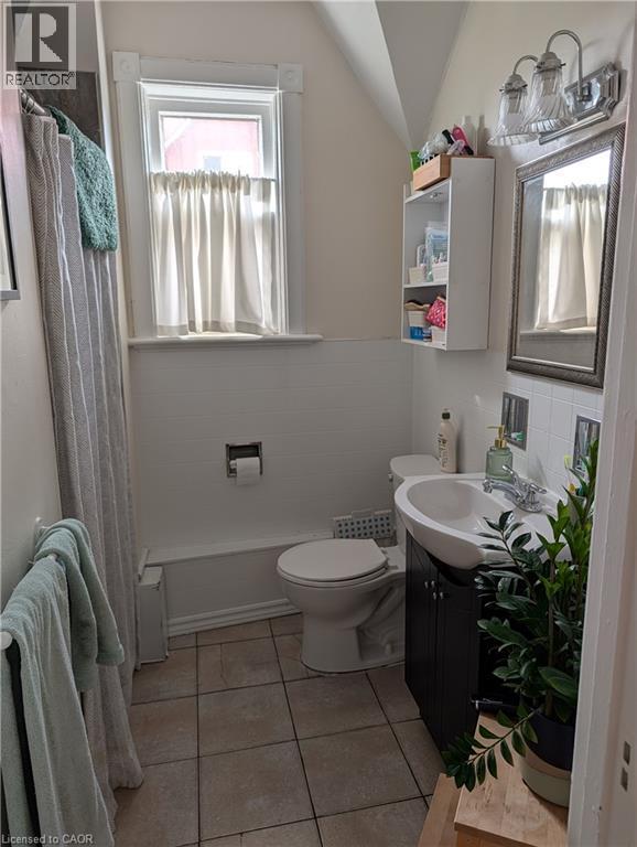 Bathroom featuring a white bathtub, toilet, and a vanity with an integrated sink - 15 Martin Street, Kitchener, ON