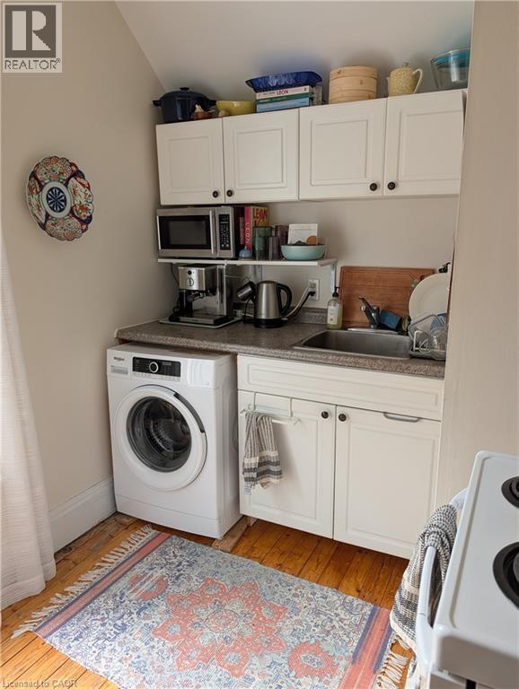 Compact kitchen area featuring wood-finish flooring and white cabinetry - 15 Martin Street, Kitchener, ON