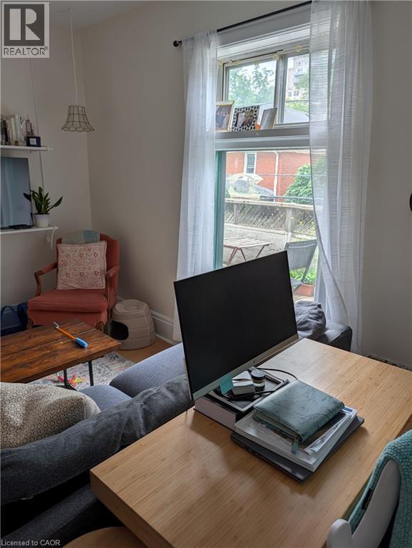 Double-hung window offering ample natural light, accompanied by white sheer curtains - 15 Martin Street, Kitchener, ON