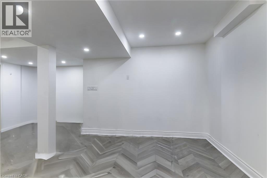 Recessed lighting illuminates a spacious room featuring a combination of light gray flooring and herringbone wood-finish flooring, complemented by white walls and trim - 252 Thorner Drive Unit# Basement, Hamilton, ON