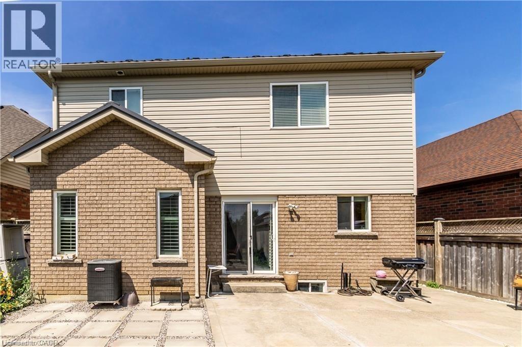 Rear exterior featuring brick and vinyl siding, multiple windows, a sliding glass door, and a paved patio area - 252 Thorner Drive Unit# Basement, Hamilton, ON