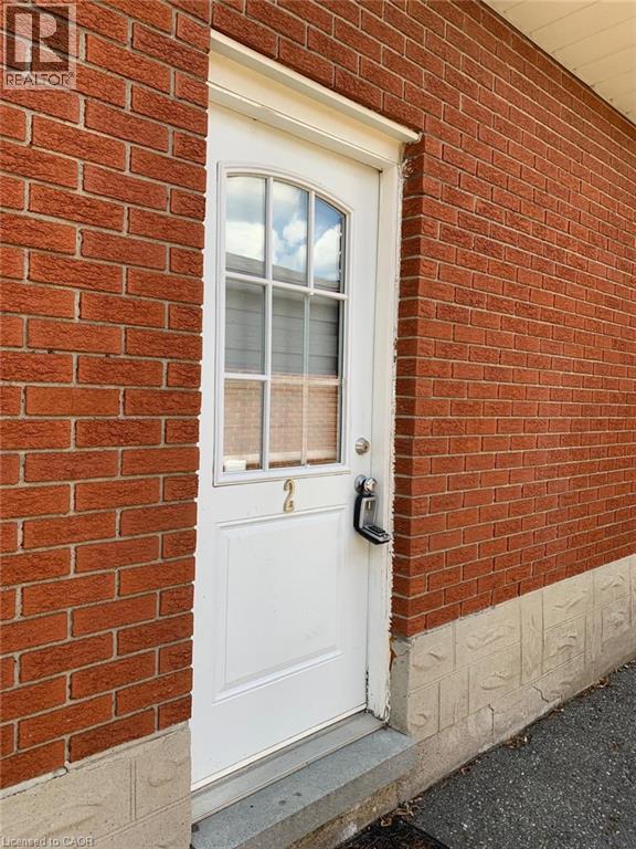 Red brick exterior with a white entry door featuring an arched window with grid detailing - 58 Farrier Drive Unit# Basement, Kitchener, ON - Outdoor With Exterior