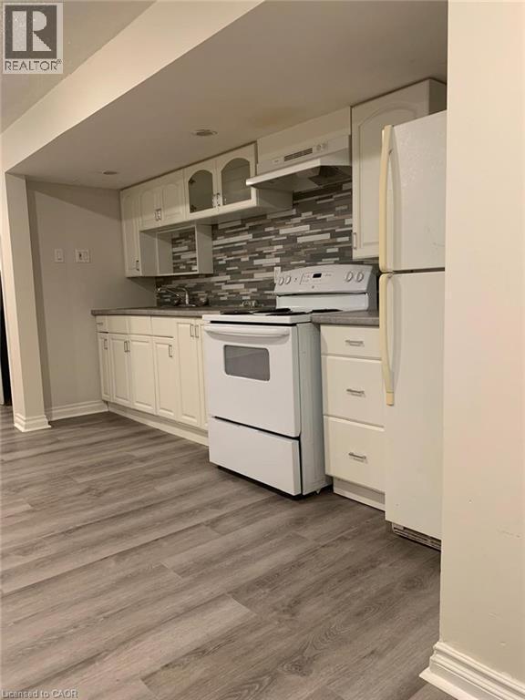 Kitchen featuring white cabinetry, gray and white tile backsplash, white appliances, and wood-finish flooring - 58 Farrier Drive Unit# Basement, Kitchener, ON - Indoor Photo Showing Kitchen
