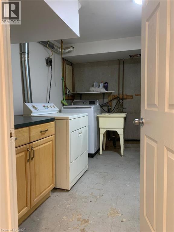 Dedicated utility space featuring a laundry sink, wood-finish cabinetry with dark countertops, and exposed ductwork - 58 Farrier Drive Unit# Basement, Kitchener, ON - Indoor Photo Showing Laundry Room