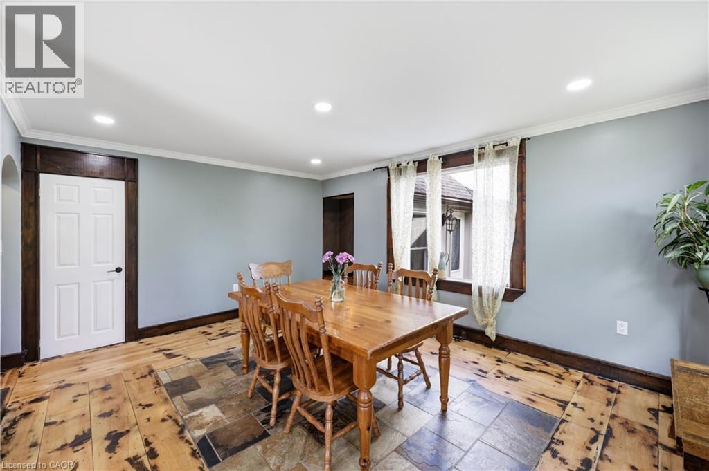 Dining room featuring light blue walls, white crown molding, recessed lighting, and a window with dark wood trim - 97 Smith Road, Hamilton, ON