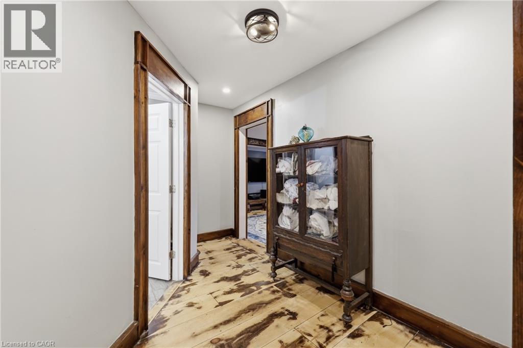 Hallway featuring wood-finish flooring, white walls, and dark wood trim - 97 Smith Road, Hamilton, ON