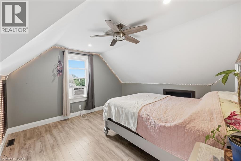 Vaulted ceiling room featuring wood-finish flooring, a window with natural light, a ceiling fan, and built-in storage - 97 Smith Road, Hamilton, ON