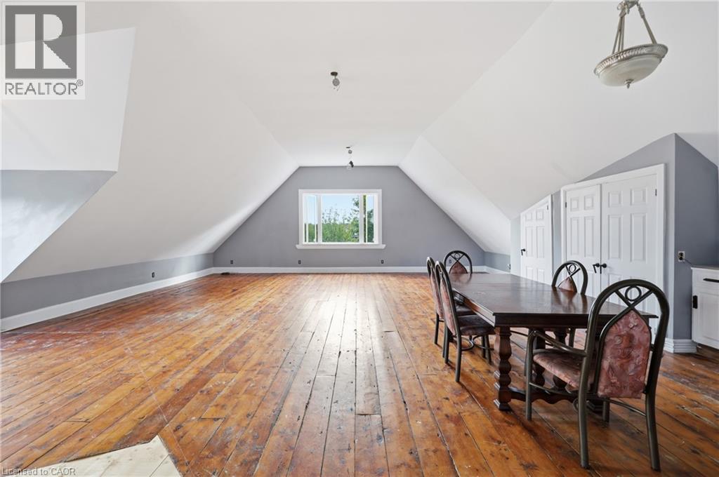 Expansive attic space featuring exposed wood flooring, a window providing natural light, and sloped ceilings - 97 Smith Road, Hamilton, ON
