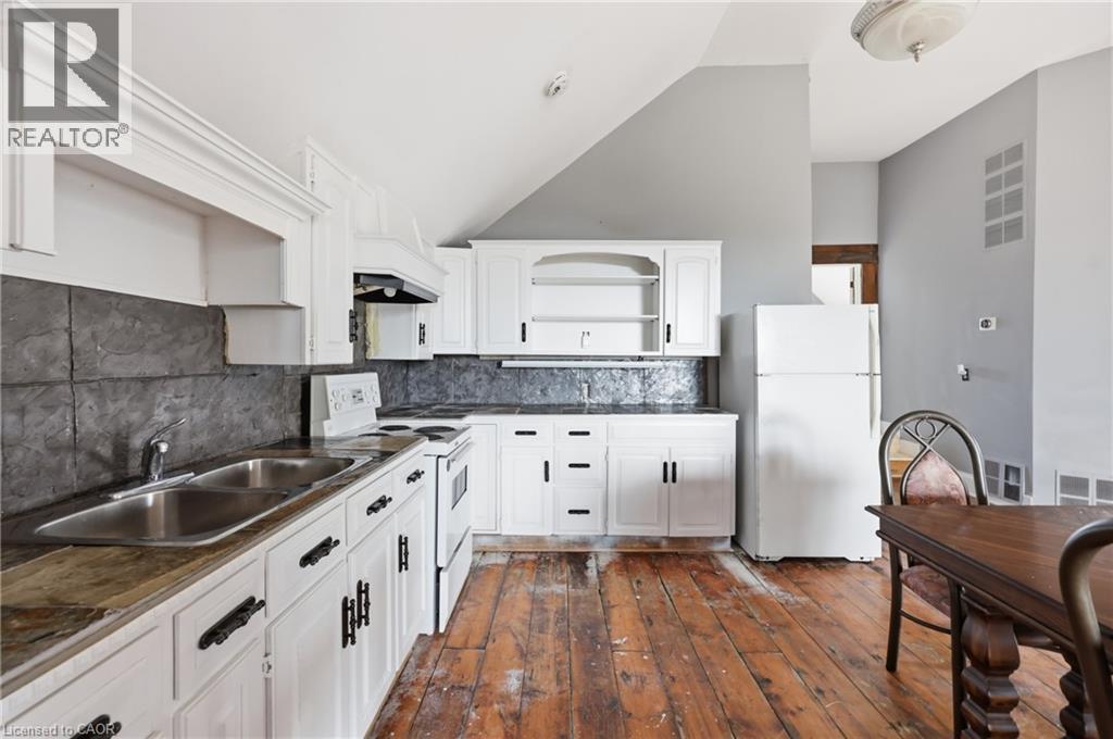 Kitchen featuring white cabinetry, a double basin sink, stone-finish countertops, and distressed wood flooring - 97 Smith Road, Hamilton, ON