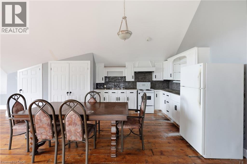 Kitchen and dining area featuring white cabinetry, dark countertops, and a full suite of white appliances - 97 Smith Road, Hamilton, ON