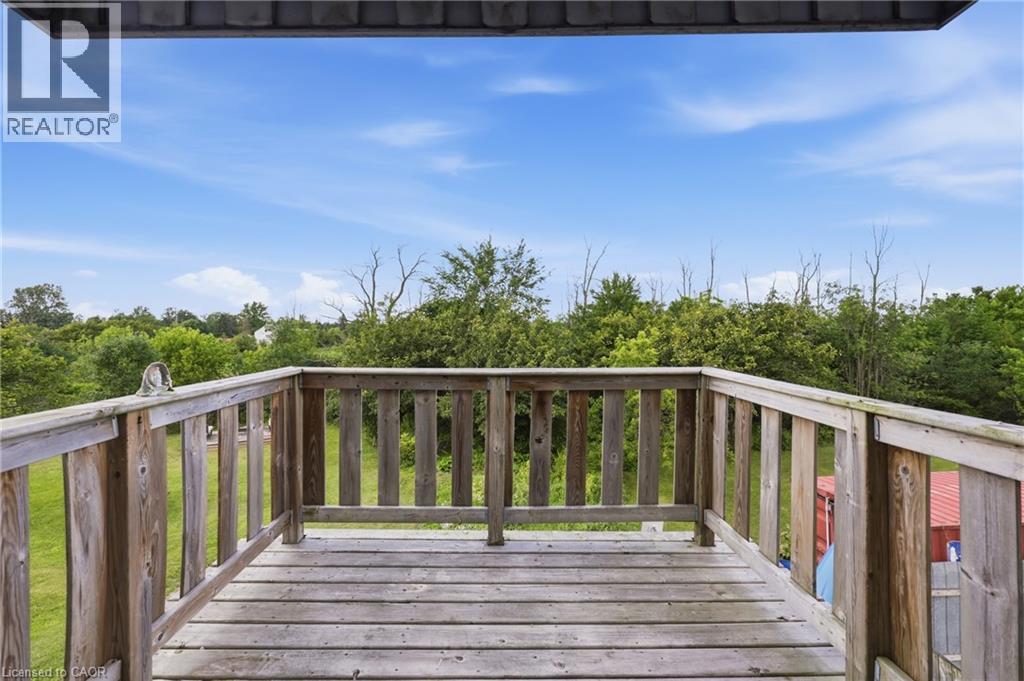 Elevated wooden deck with baluster railing, overlooking expansive green space with mature trees - 97 Smith Road, Hamilton, ON