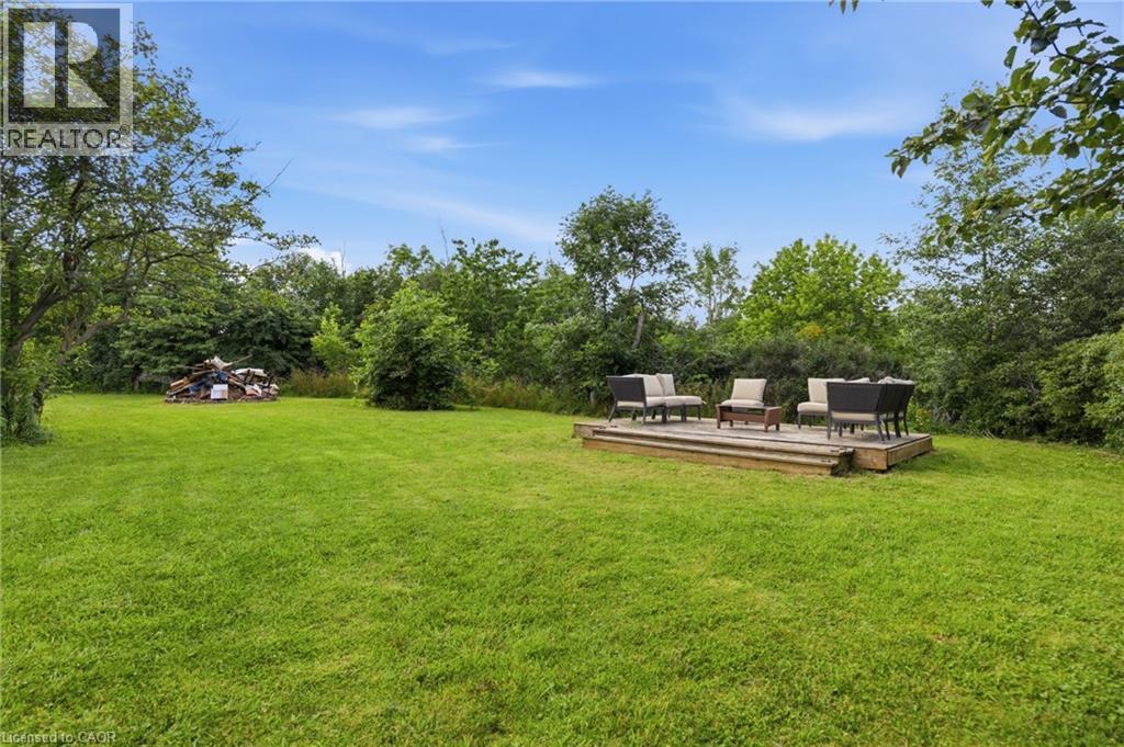 Expansive rear yard featuring a wooden deck with a low profile, surrounded by a lush green lawn - 97 Smith Road, Hamilton, ON