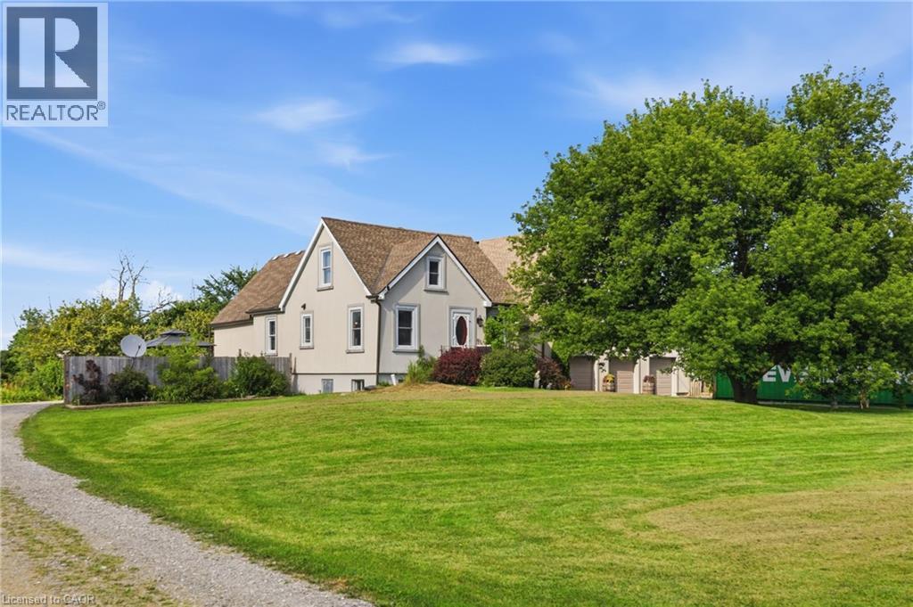Gable-roof property featuring a light-colored exterior with white trim, a gravel driveway, and a spacious green lawn - 97 Smith Road, Hamilton, ON