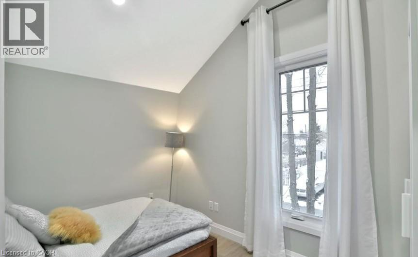 Bright room with a large window, light gray walls, recessed lighting, and wood-finish flooring - 33 Hawthorne Avenue, Hamilton, ON