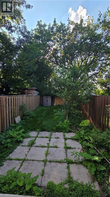 Fenced backyard featuring a paver patio area, green lawn space, and mature trees - 33 Hawthorne Avenue, Hamilton, ON
