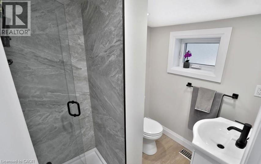 Glass-enclosed shower with large format tile surround, featuring a matte black handle - 33 Hawthorne Avenue, Hamilton, ON