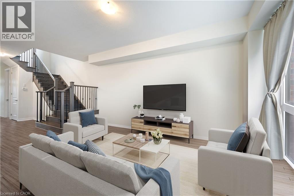 Spacious living area featuring wood-finish flooring, a contemporary staircase with dark wood treads and metal balusters, and large windows with privacy drapes - 61 Vanilla Trail, Thorold, ON