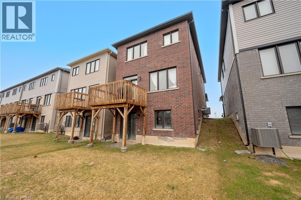 Brick and siding exterior featuring multiple windows and a wooden deck - 61 Vanilla Trail, Thorold, ON