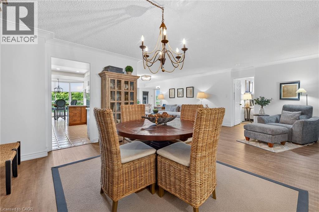Dining area featuring a circular wood table and an ornate chandelier - 1237 North Shore Boulevard Unit# 405, Burlington, ON - Indoor Photo Showing Dining Room