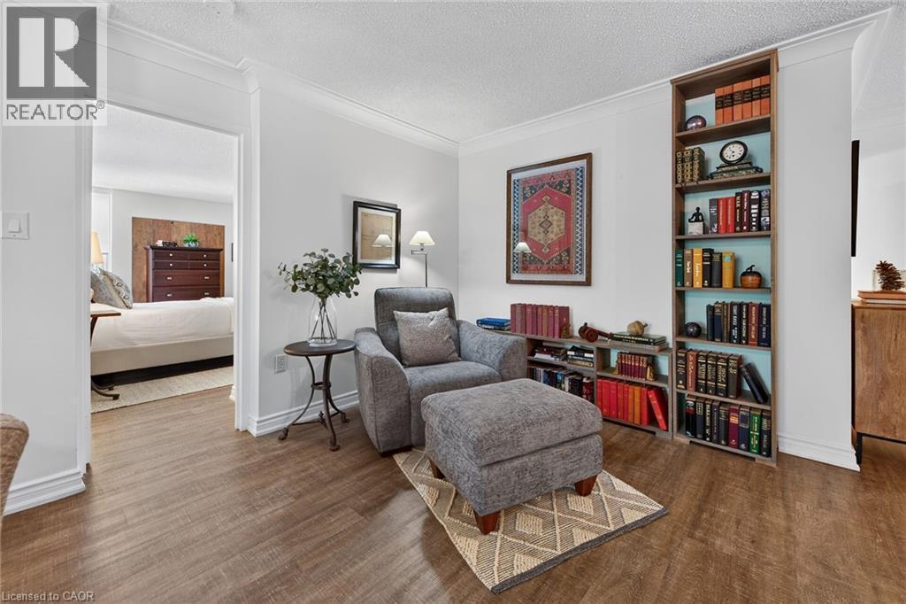 Wood-finish flooring throughout, featuring crown molding, built-in shelving, and a clear doorway opening - 1237 North Shore Boulevard Unit# 405, Burlington, ON - Indoor Photo Showing Living Room