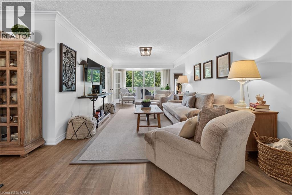Open concept living space featuring wood-finish flooring and crown molding - 1237 North Shore Boulevard Unit# 405, Burlington, ON - Indoor Photo Showing Living Room