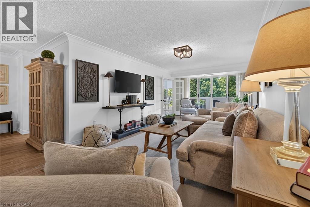 Living area featuring crown molding, neutral wall tones, and wood-finish flooring - 1237 North Shore Boulevard Unit# 405, Burlington, ON - Indoor Photo Showing Living Room