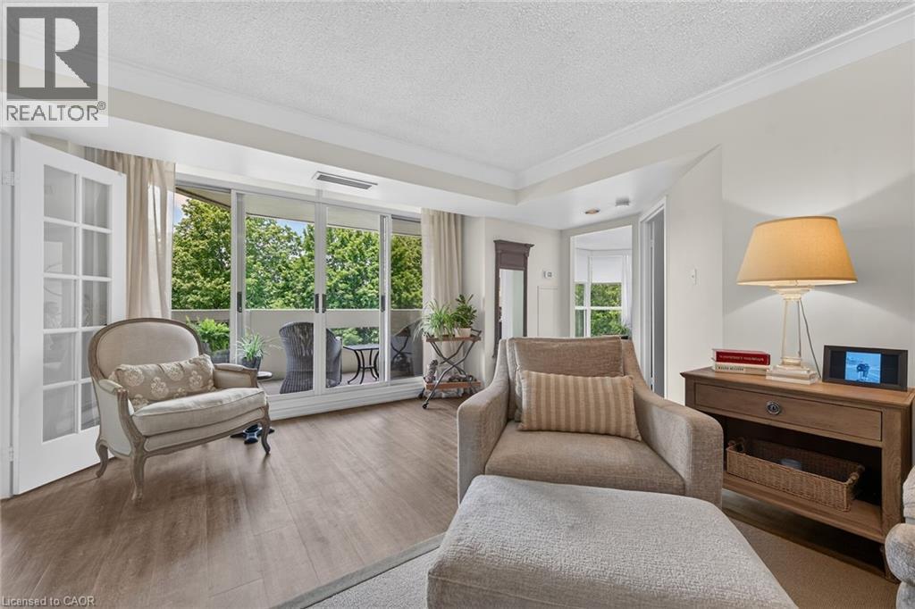 Living area featuring wood-finish flooring, crown molding, and a tray ceiling - 1237 North Shore Boulevard Unit# 405, Burlington, ON - Indoor Photo Showing Living Room