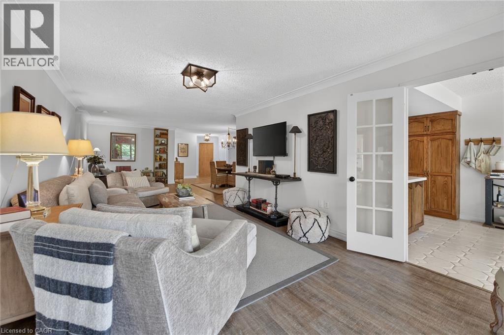 Open-concept living area featuring wood-finish flooring, white crown molding, and a modern flush-mount ceiling light fixture - 1237 North Shore Boulevard Unit# 405, Burlington, ON - Indoor Photo Showing Living Room
