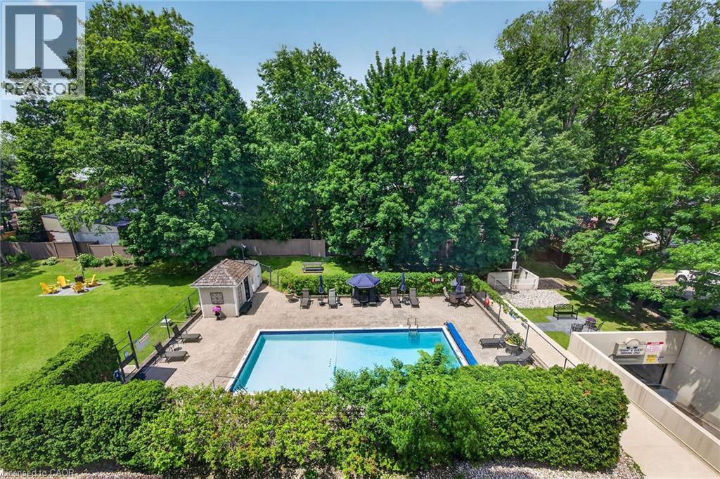 Outdoor swimming pool with surrounding paver patio and mature tree landscaping - 1237 North Shore Boulevard Unit# 405, Burlington, ON - Outdoor With In Ground Pool With Backyard