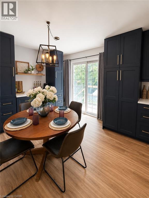 Kitchen area featuring extensive dark cabinetry, wood-finish flooring, a contemporary pendant light fixture, sliding glass doors, and open wood shelving - 355 East 36Th Street, Hamilton, ON
