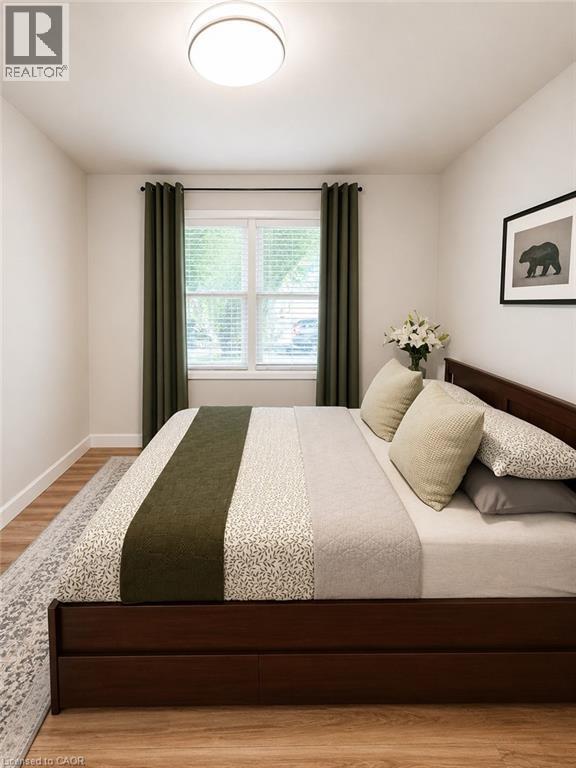 Light-filled room featuring wood-finish flooring, white walls, and a large window with white blinds - 355 East 36Th Street, Hamilton, ON