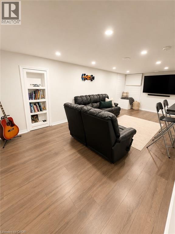 Spacious room featuring wood-finish flooring, recessed lighting, and a built-in bookshelf - 355 East 36Th Street, Hamilton, ON