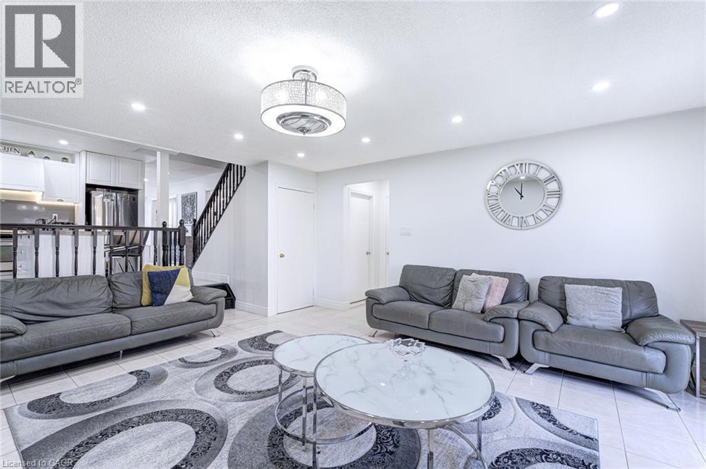 Open-concept living area featuring light-colored tile flooring, white walls, and recessed lighting - 214 Merrilee Crescent, Hamilton, ON