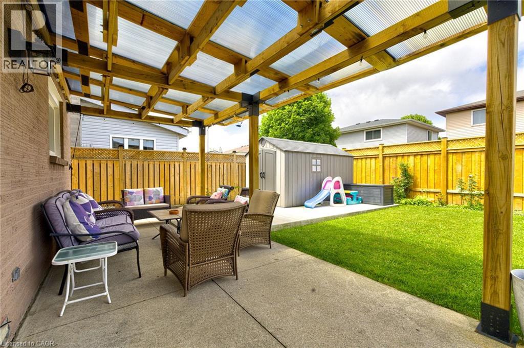 Covered patio featuring a concrete surface, wood pergola with translucent roofing, and direct access to a grass lawn - 214 Merrilee Crescent, Hamilton, ON