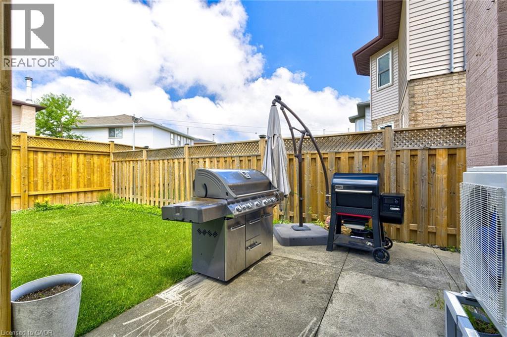 Private backyard featuring a concrete patio and a perimeter wood fence with lattice accents - 214 Merrilee Crescent, Hamilton, ON