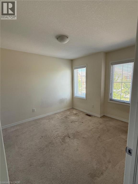 Carpeted room featuring two windows with horizontal blinds, a white ceiling, and a flush mount light fixture - 63 Ridge Road Unit# Upper, Cambridge, ON