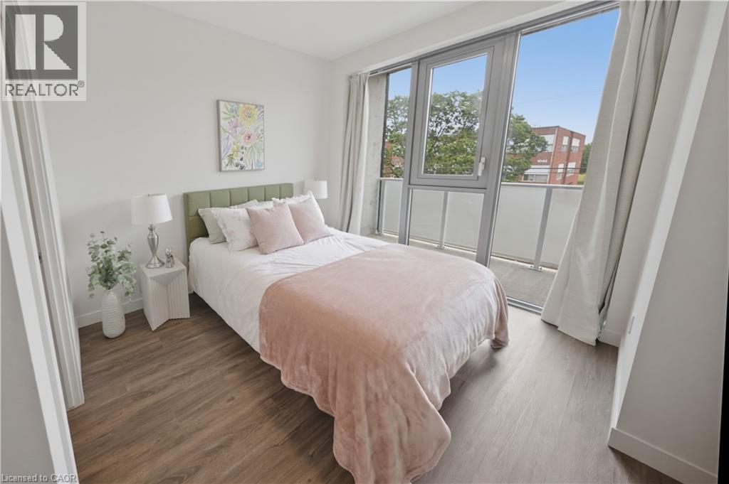 Room featuring wood-finish flooring, white walls, and a full-height glass door opening to a private balcony - 1055 Weber Street E Unit# 207, Kitchener, ON