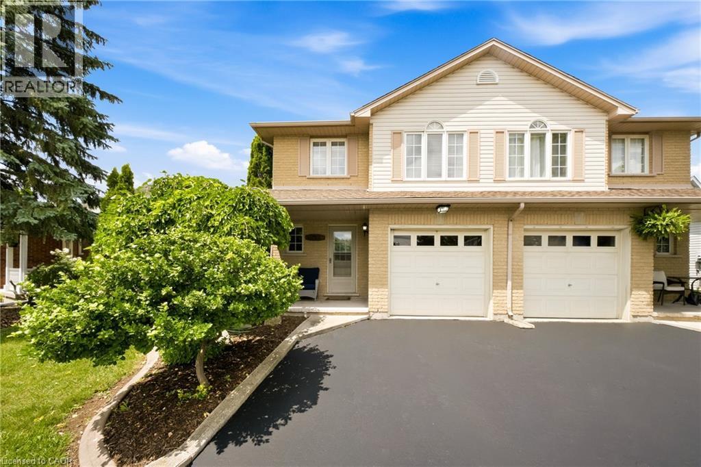 Two-story property featuring a brick and siding exterior, a two-car garage, and a paved driveway - 16 Scottacres Boulevard, Caledonia, ON