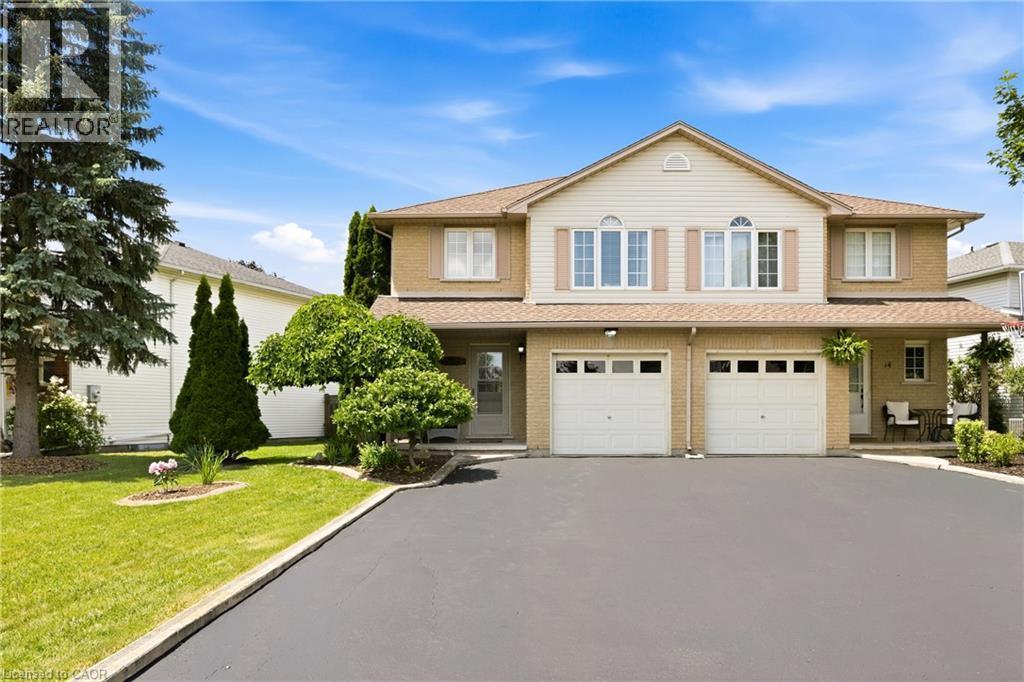 Two-story residence featuring brick and siding facade, dual garage doors, and a covered porch entry - 16 Scottacres Boulevard, Caledonia, ON